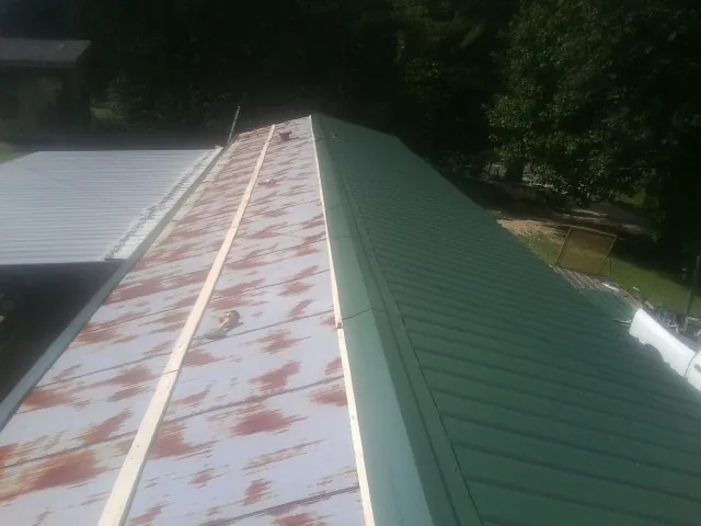 Old rusted panels beside newly installed green metal roofing — Wind Damage Roof Repair by Roofing Brothers in Buffalo