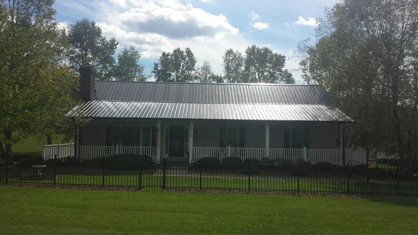 Gray metal roof on a brick ranch with a full width front porch — Gutter Guard Installation work by our crew in Buffalo